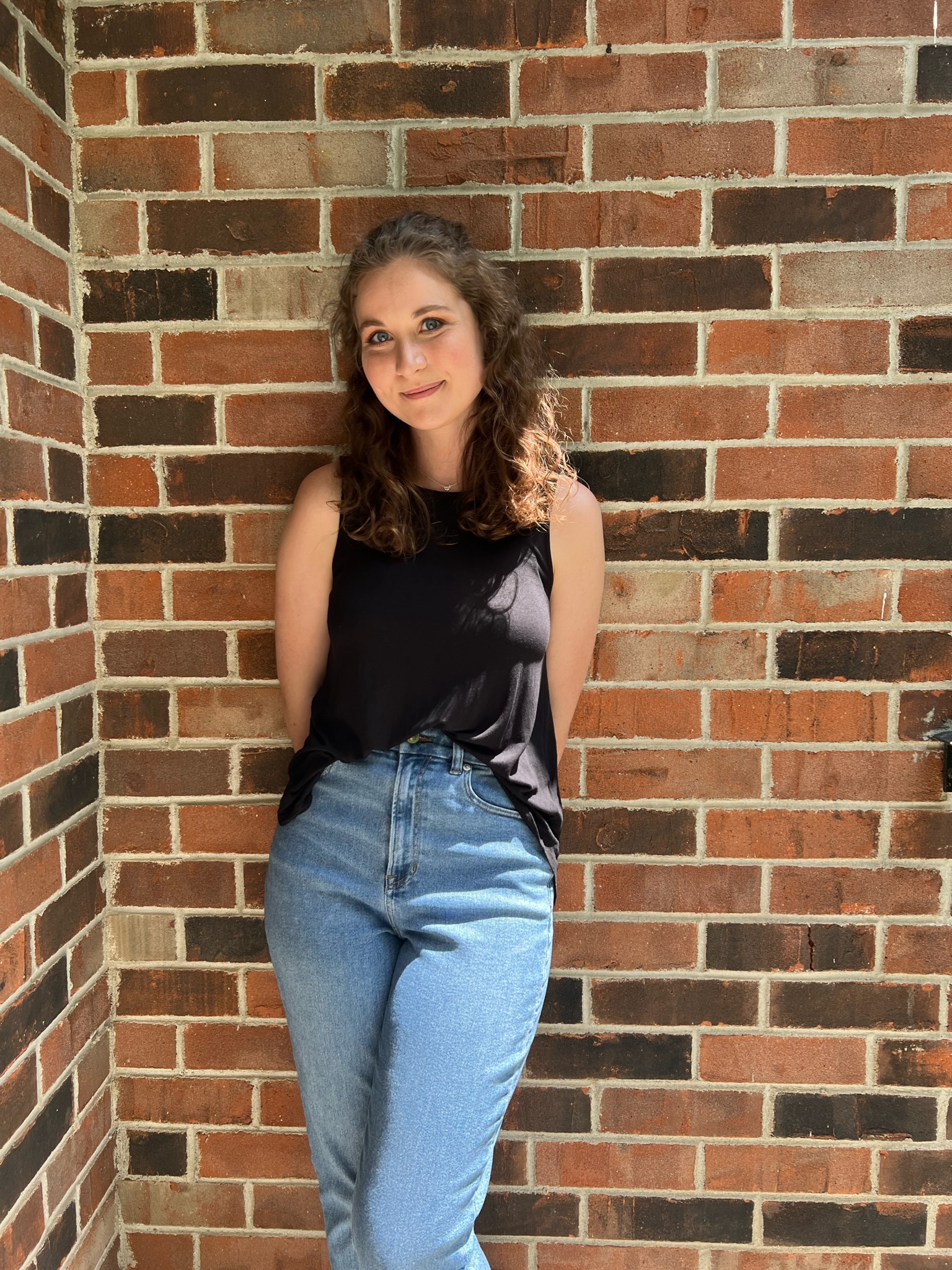 photo of the author, Erin Paulson, standing against a brick wall, smiling