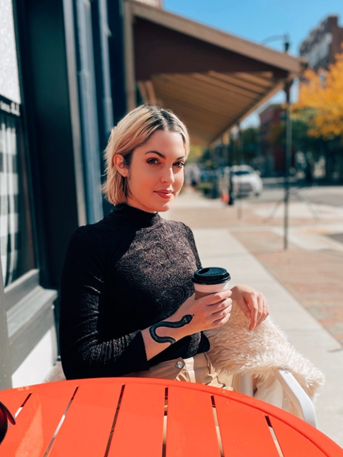 headshot of Monica Wolfe sitting at a table and holding a coffee cup