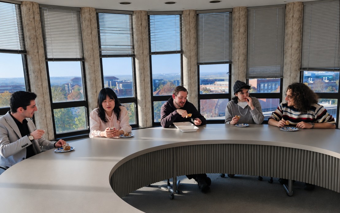 Graduate students sitting at a large circular table.
