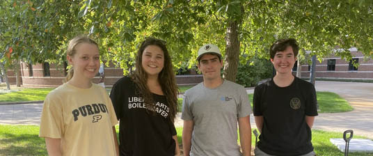 Undergraduate students standing underneath a tree