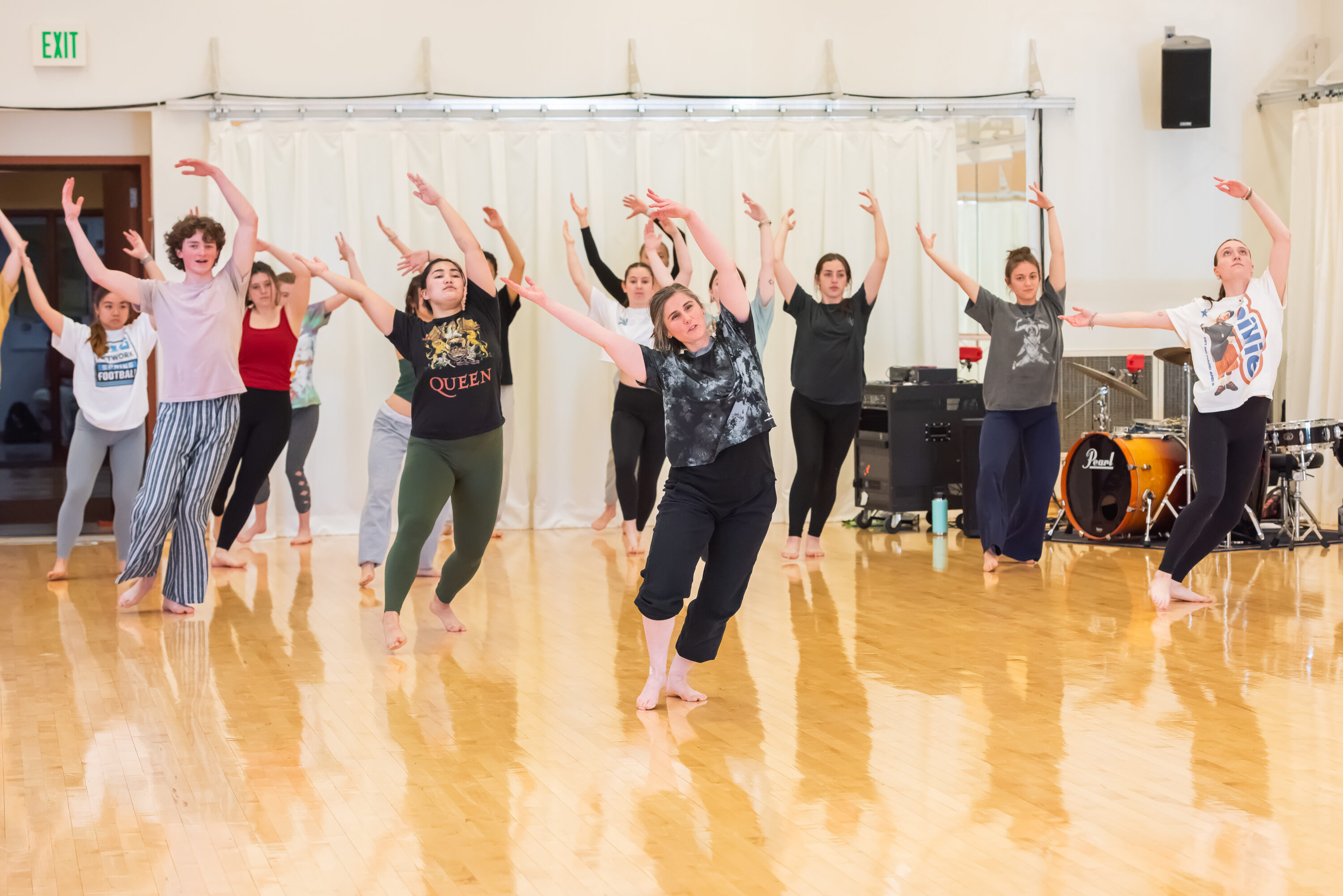 A group of students in the dance studio following the dance instructor.