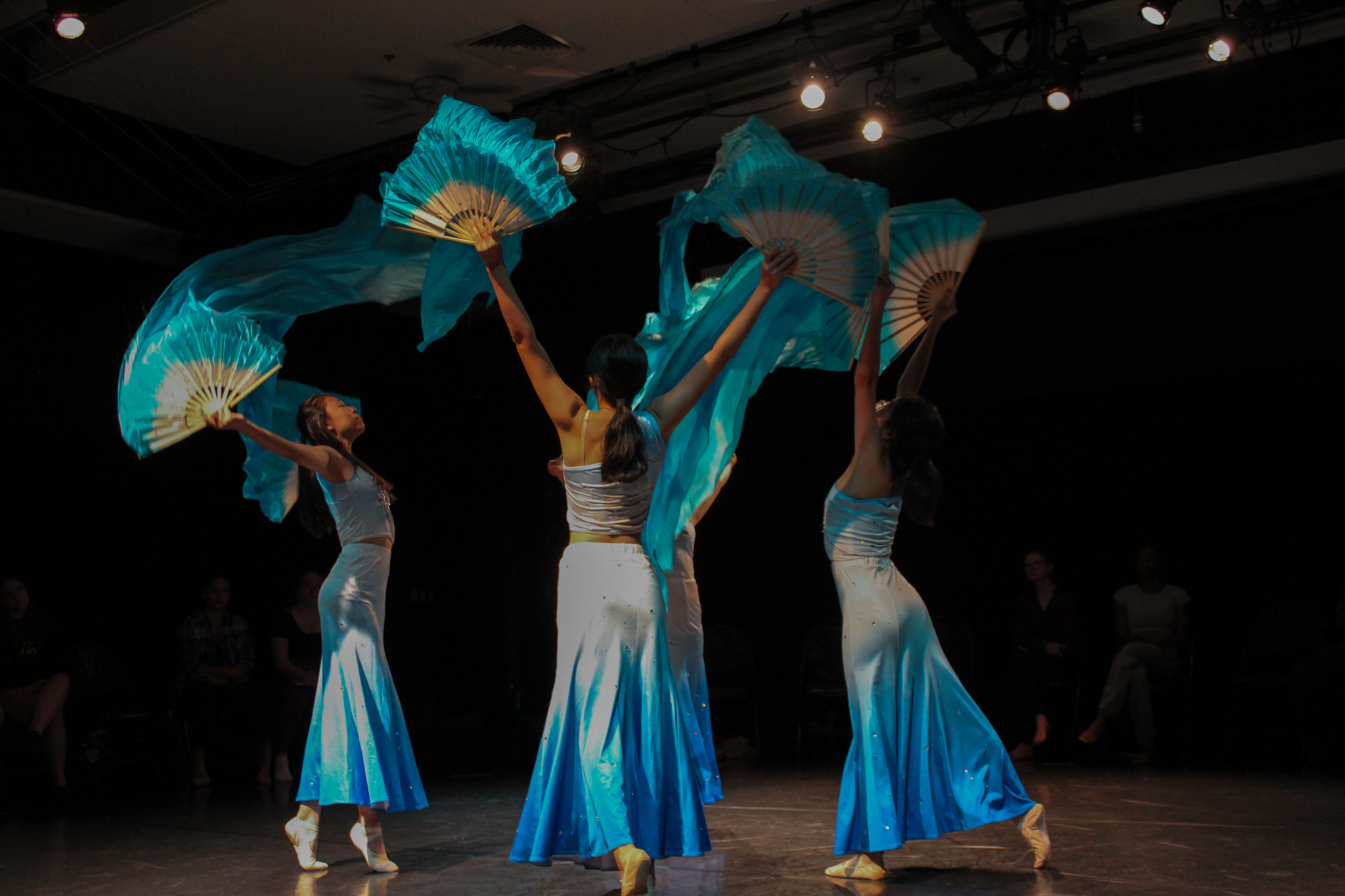 Dancers standing on stage with Blue and white fans