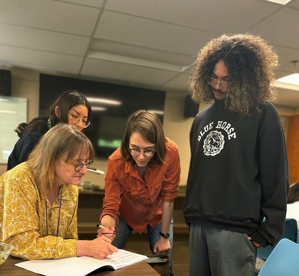 Four people looking down at a notebook