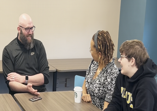 students and faculty sitting at a table laughing