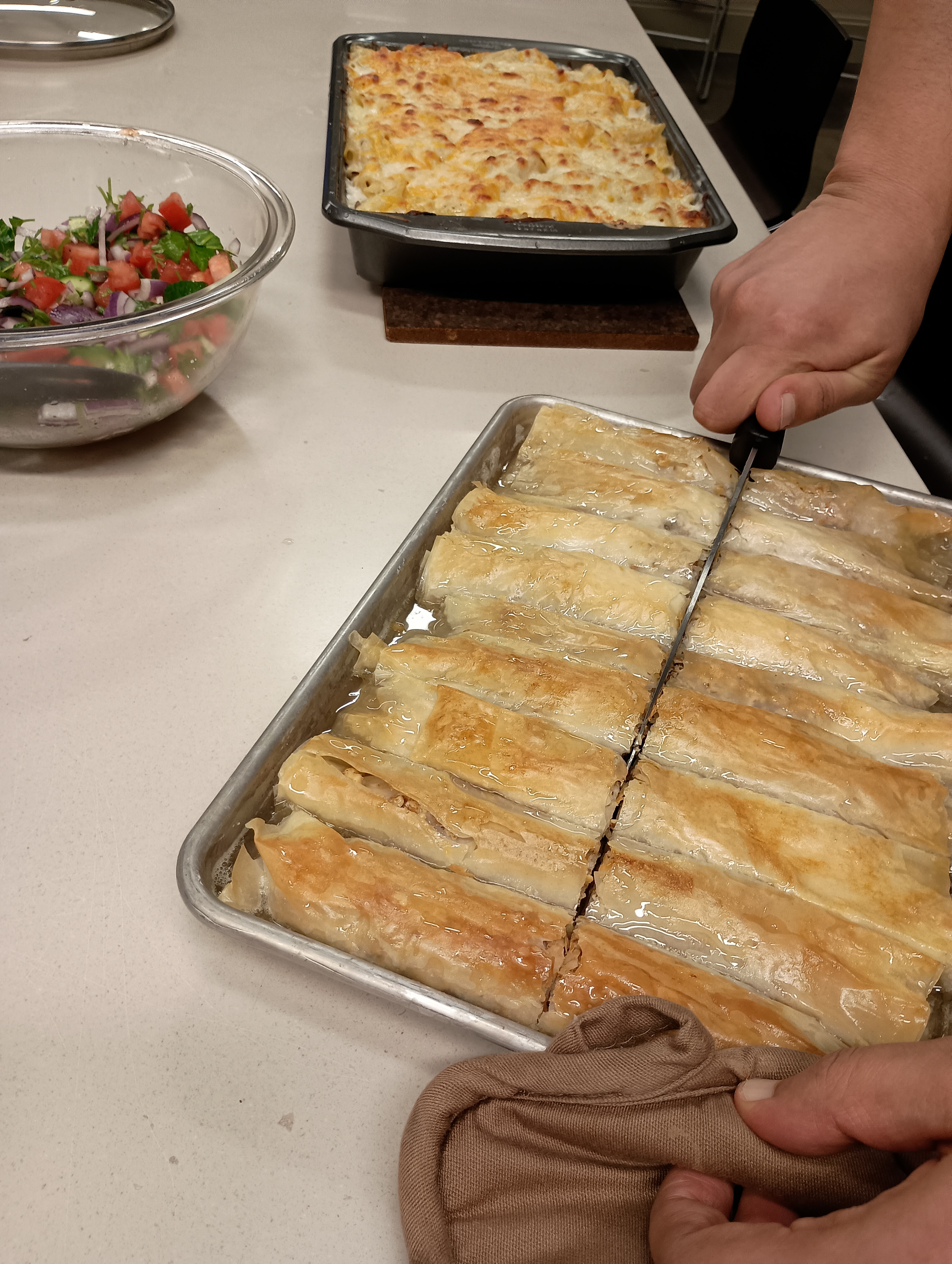 Person Cutting a Tray of Baclava Pastry in Kitchen Lab