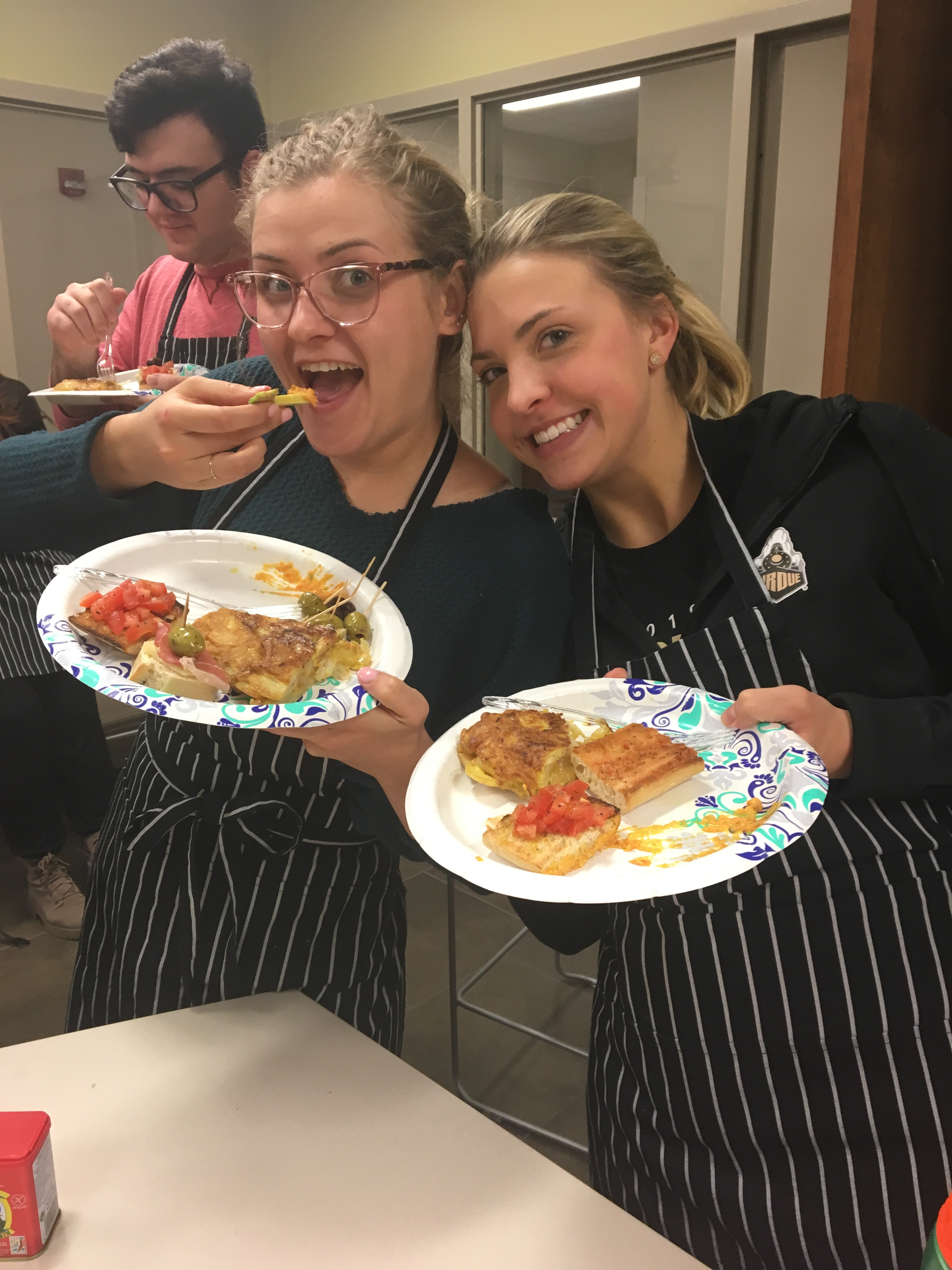 wo Students Smiling and Showing Plates of Food During a Cooking Class