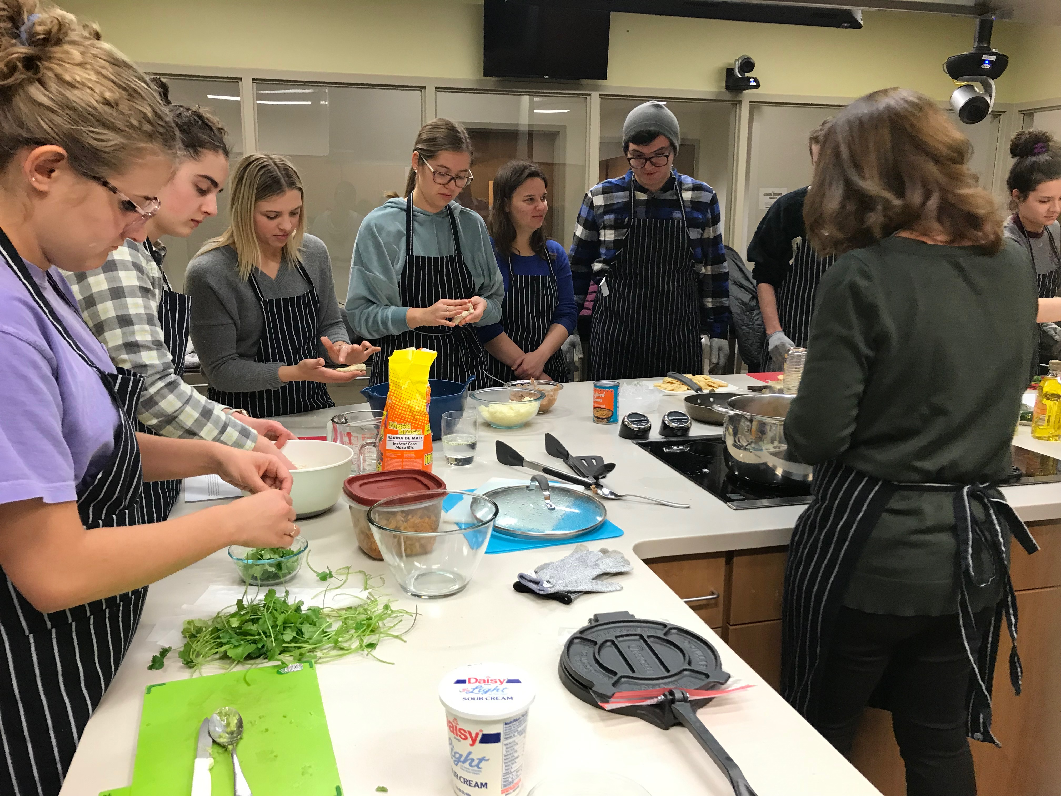 Group of Students Cooking Together Around a Kitchen Island in a Teaching Kitchen