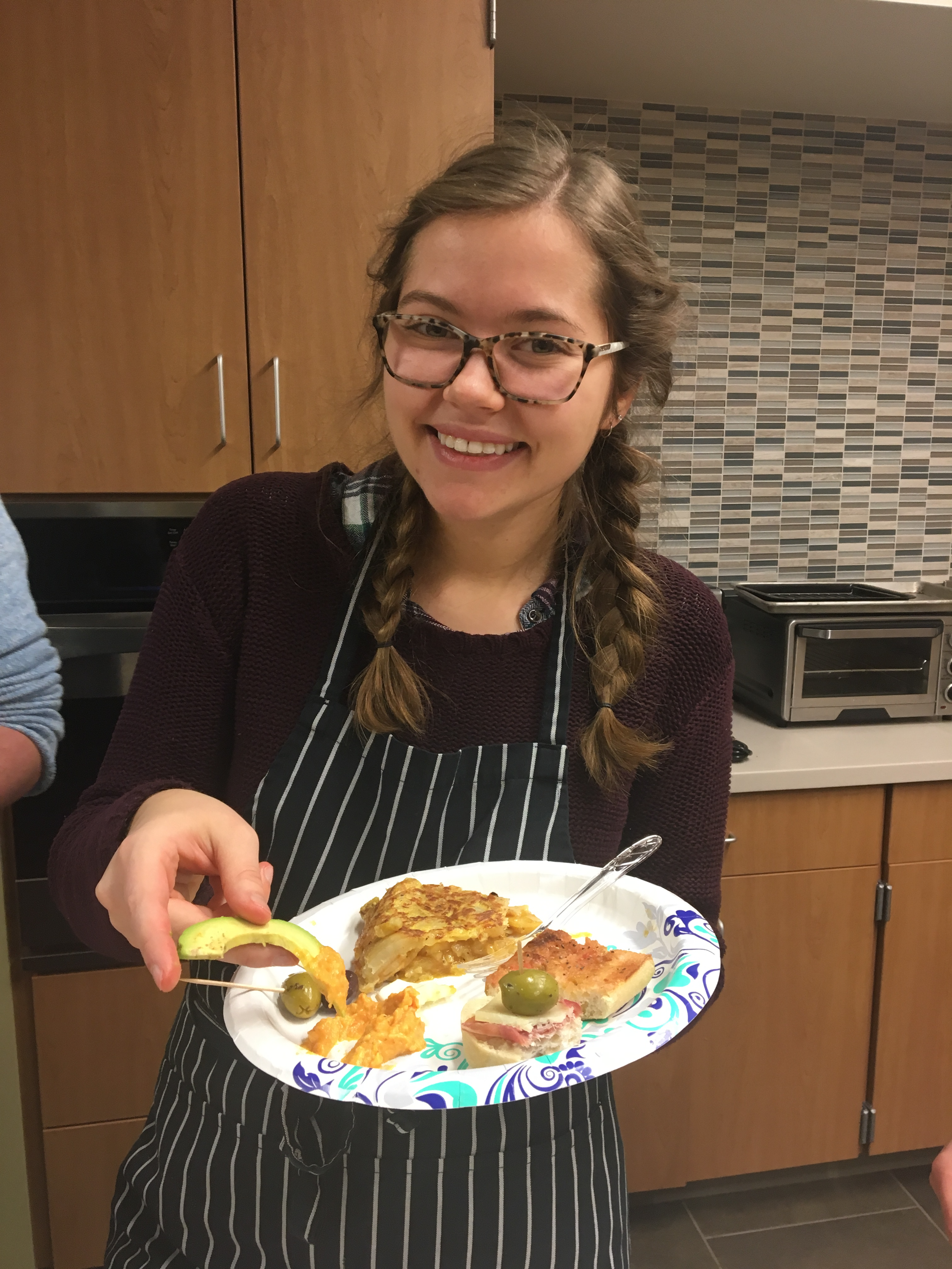 Student Smiling and Holding a Plate of Food in a Teaching Kitchen