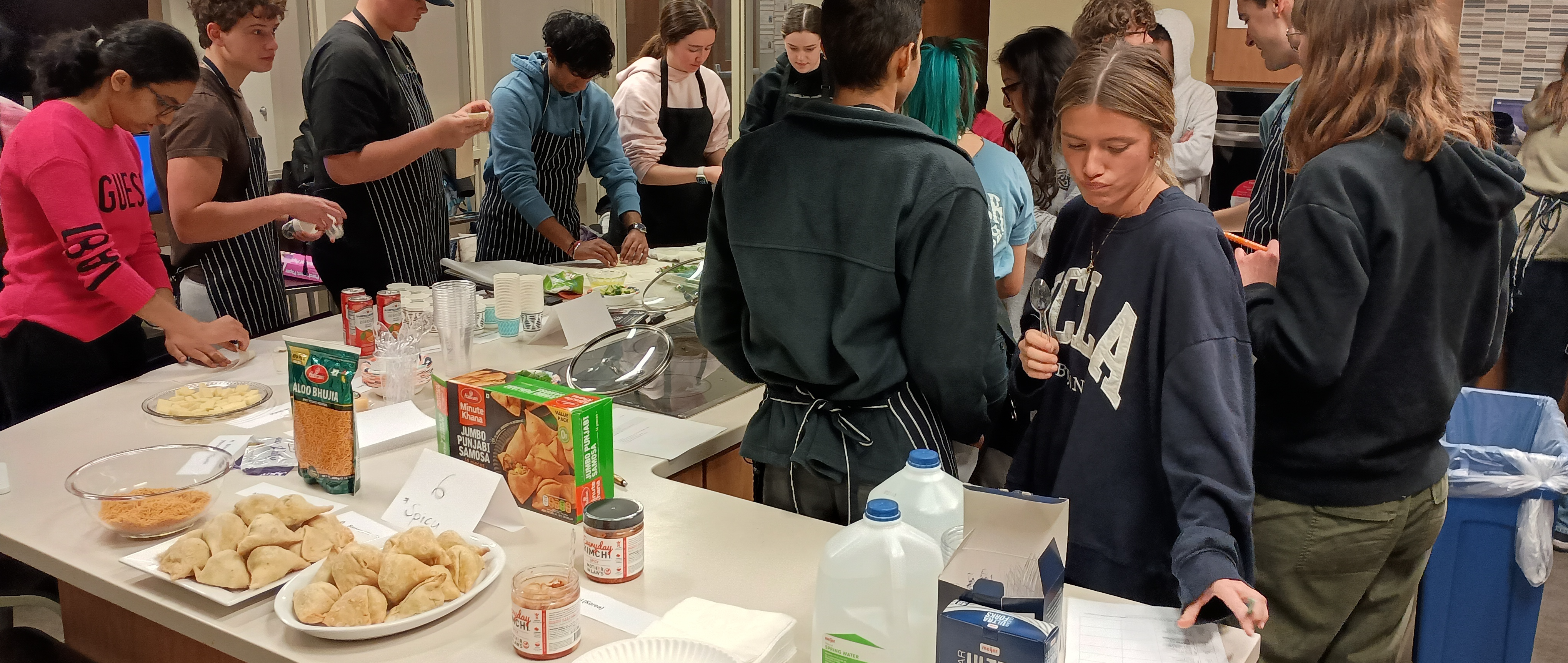 students interacting in a kitchen area with food on the counter