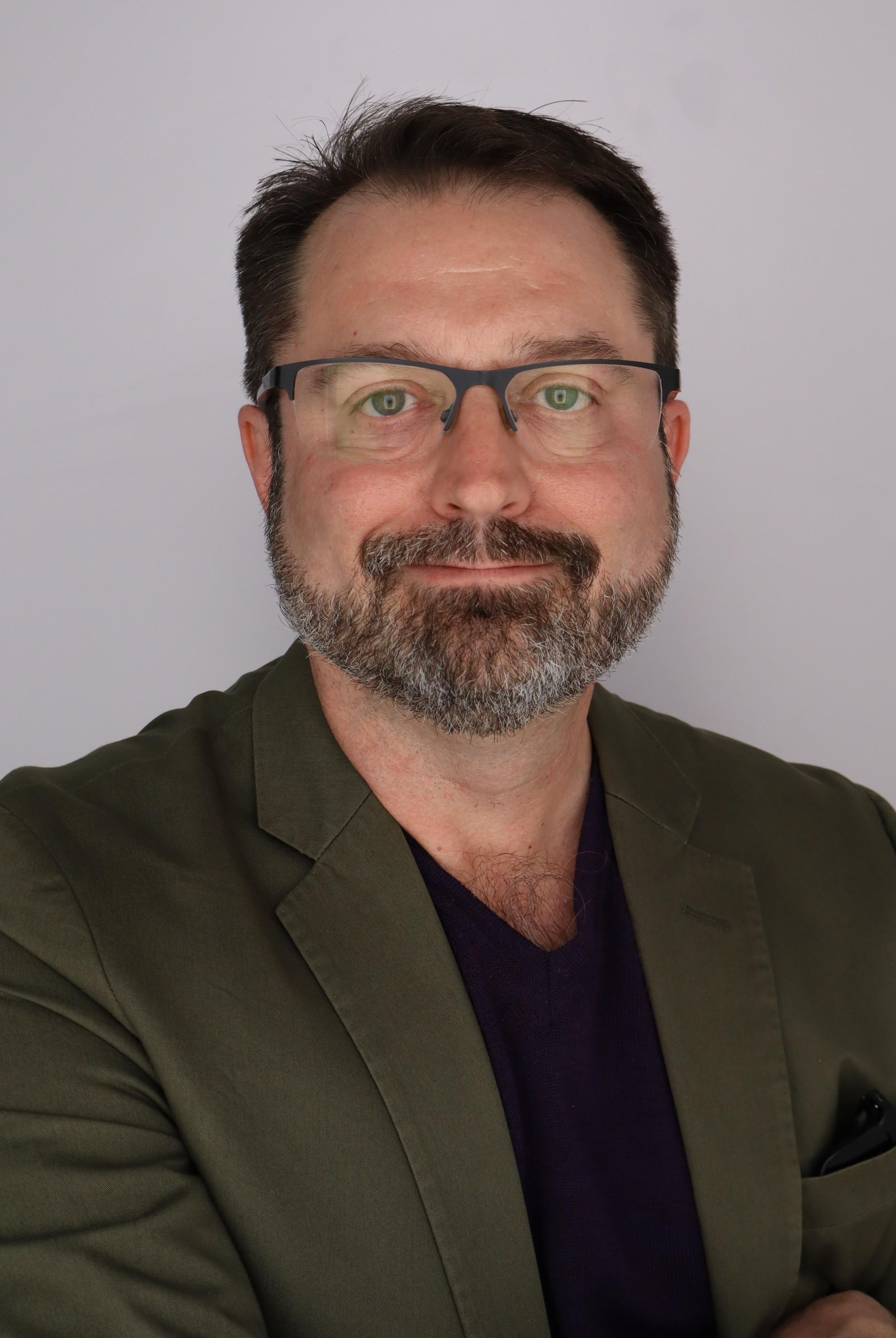 headshot of Kory Cooper. He has glasses, facial hair and a suit jacket