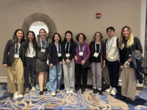 Nine people lined up against the wall wearing academic conference clothes