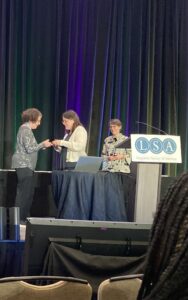 From left: woman in receiving award, woman presenting award, podium that says LSA