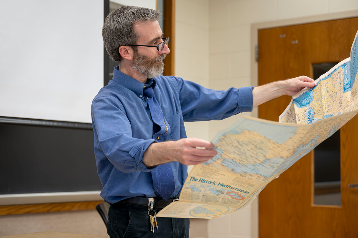A man holding a map in a classroom.