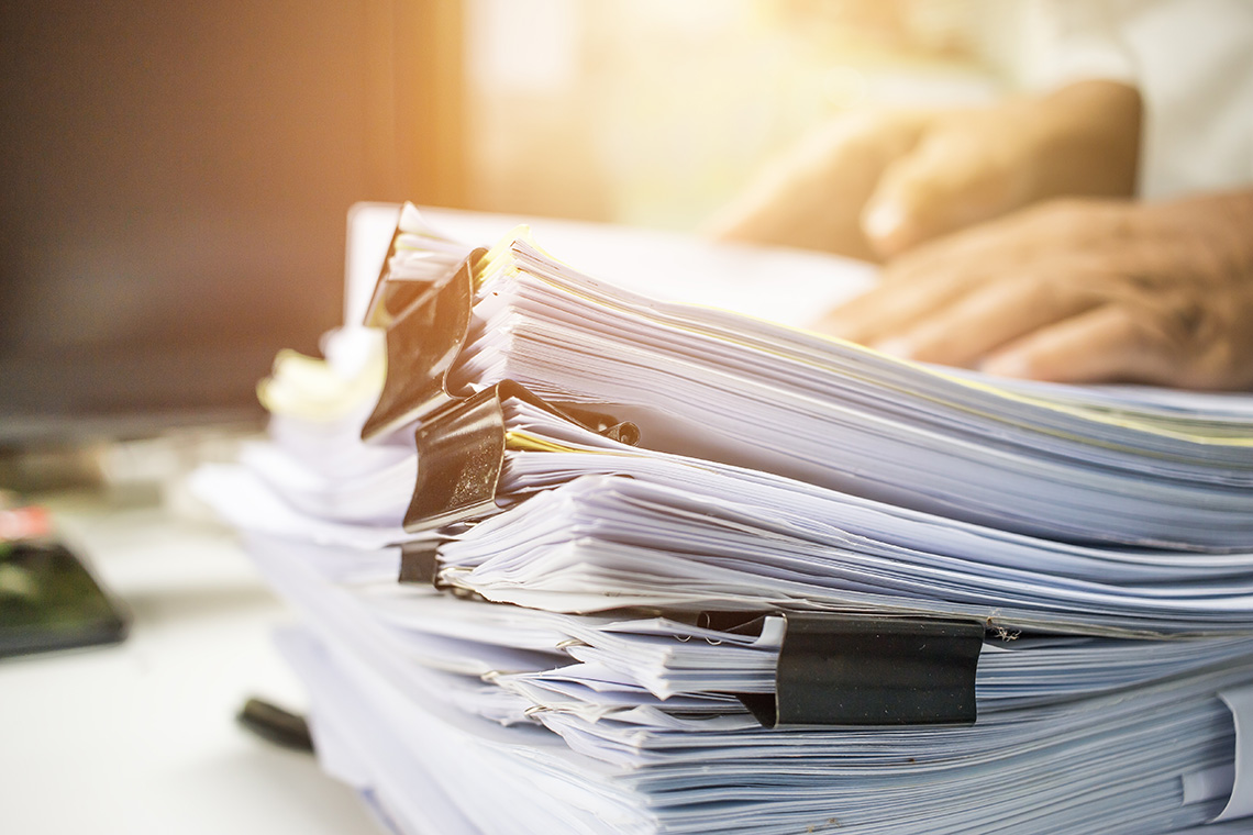 Lots opf paper documents joind together with alligator clips with hands on top of them.