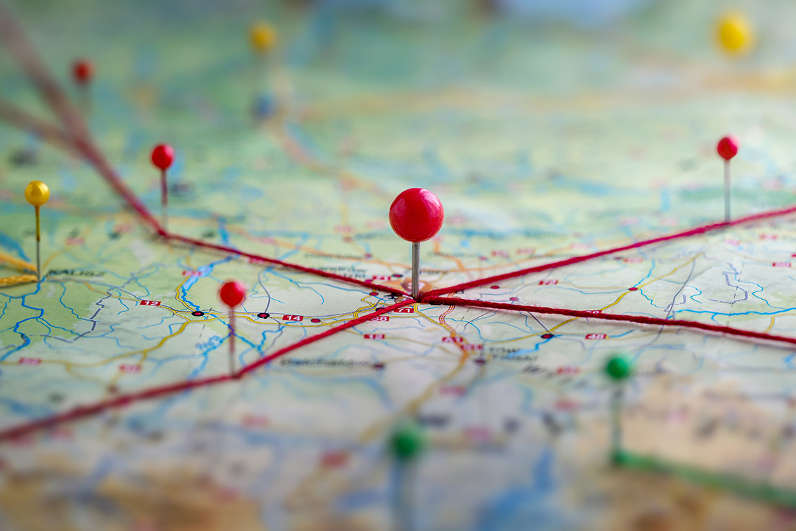 A map with pushpins at various locations with string going between them.