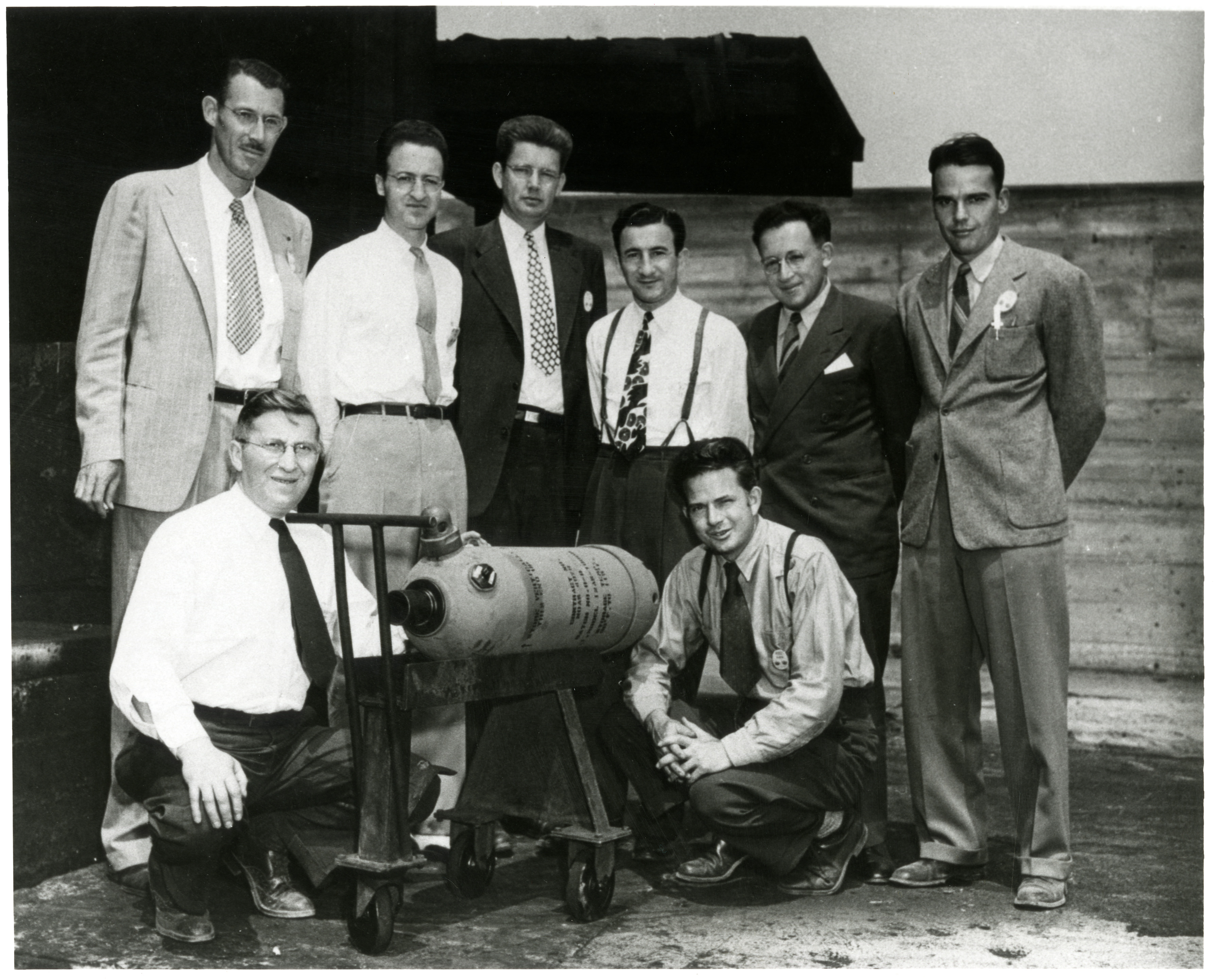 Aerojet Team for the Solid-Propellant JATO.  Left to right: front row, M.J. Zucrow, the 12 AS-1000 JATO unit, and Glenn Miller; back row, Norton Moore, A.I. Antonio, Brooks Morris, Bernie Dorman, Martin Summerfield, and Robert D. Young.