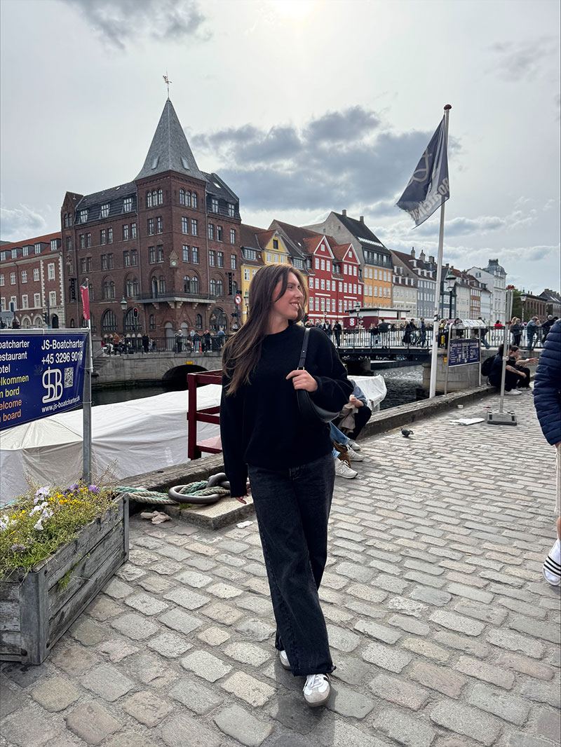 Hope Trampski standing in front of several buildings in Stockholm, Sweden.