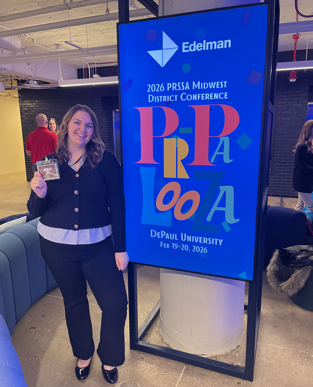 Abbey posing for a picture with signage at the PRSSA district conference.