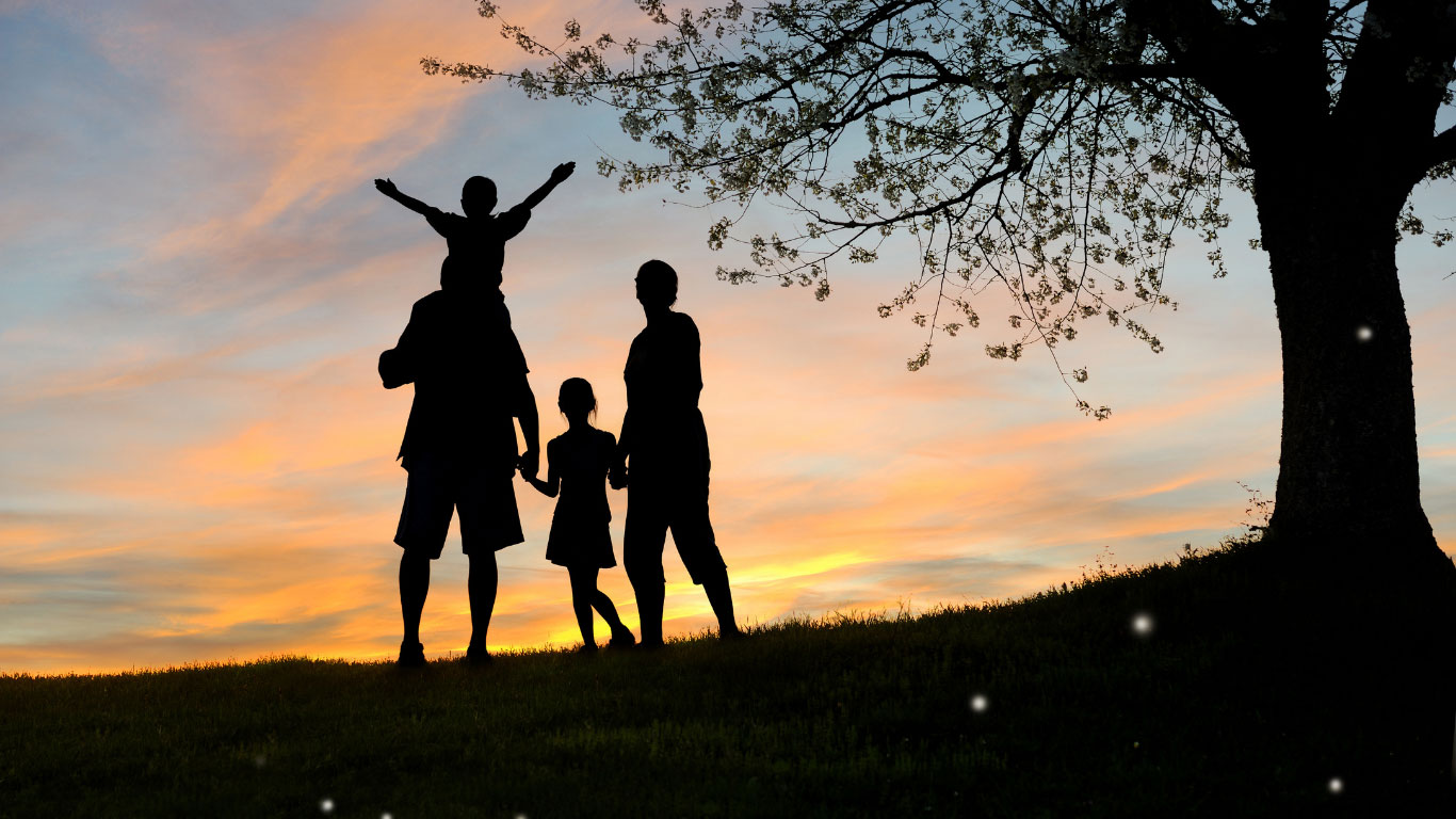 Photo taken at sunset with the silhouette of a family holding hands