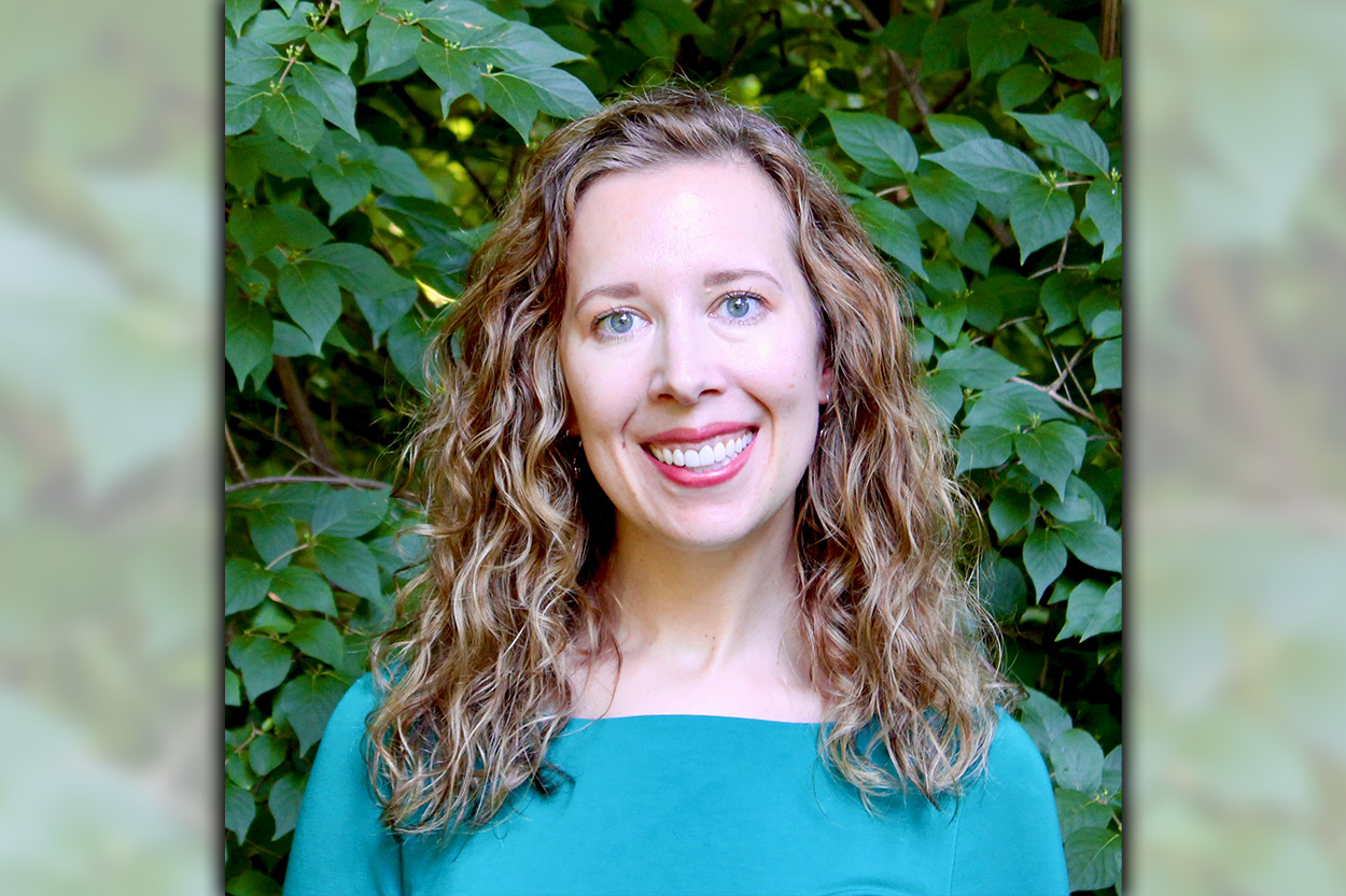 Dr. Hoewe, dressed in teal, smiles in front of trees.
