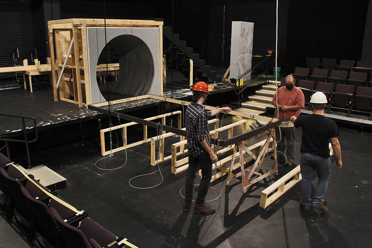 Three technicians creating a structural element for a stage environment.