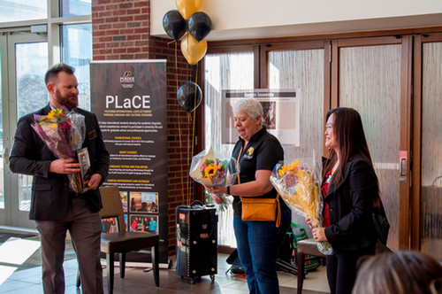 Purdue Language and Cultural Exchange (PLaCE) coordinator Suzanne Nicolas gives flowers to PLaCE Director Matt Allen and Associate Director Lixia Cheng on PLaCE 10th year anniversary (May 2024).