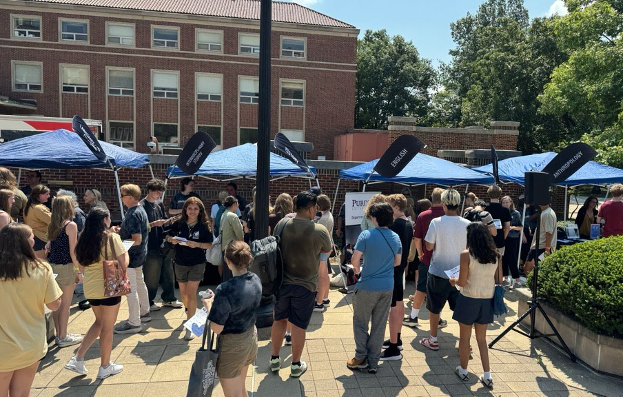 Students visiting tents featuring all CLA Departments at an event.