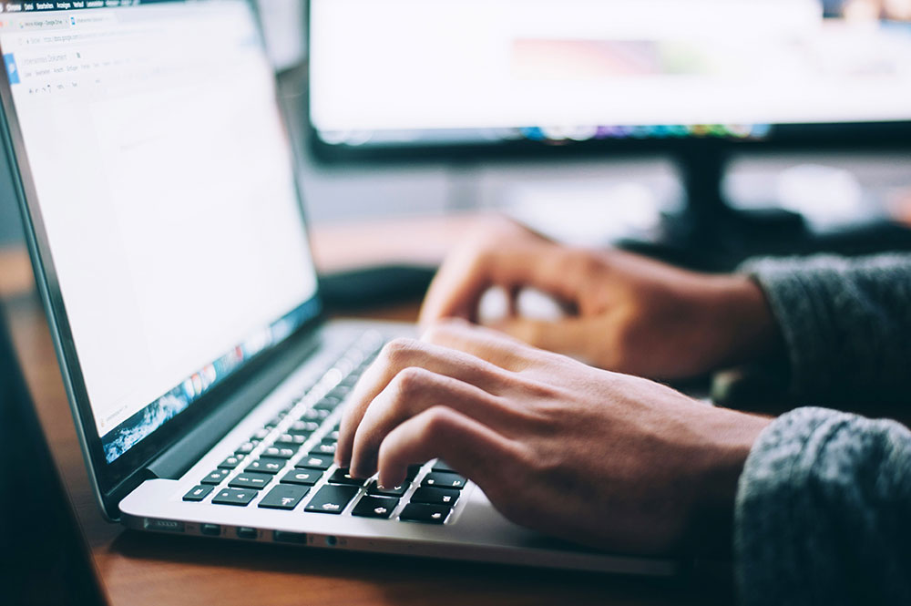Closeup of a person typing on a laptop computer.