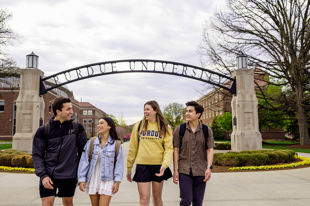 Four Purdue University students walking under the Gateway Arch.